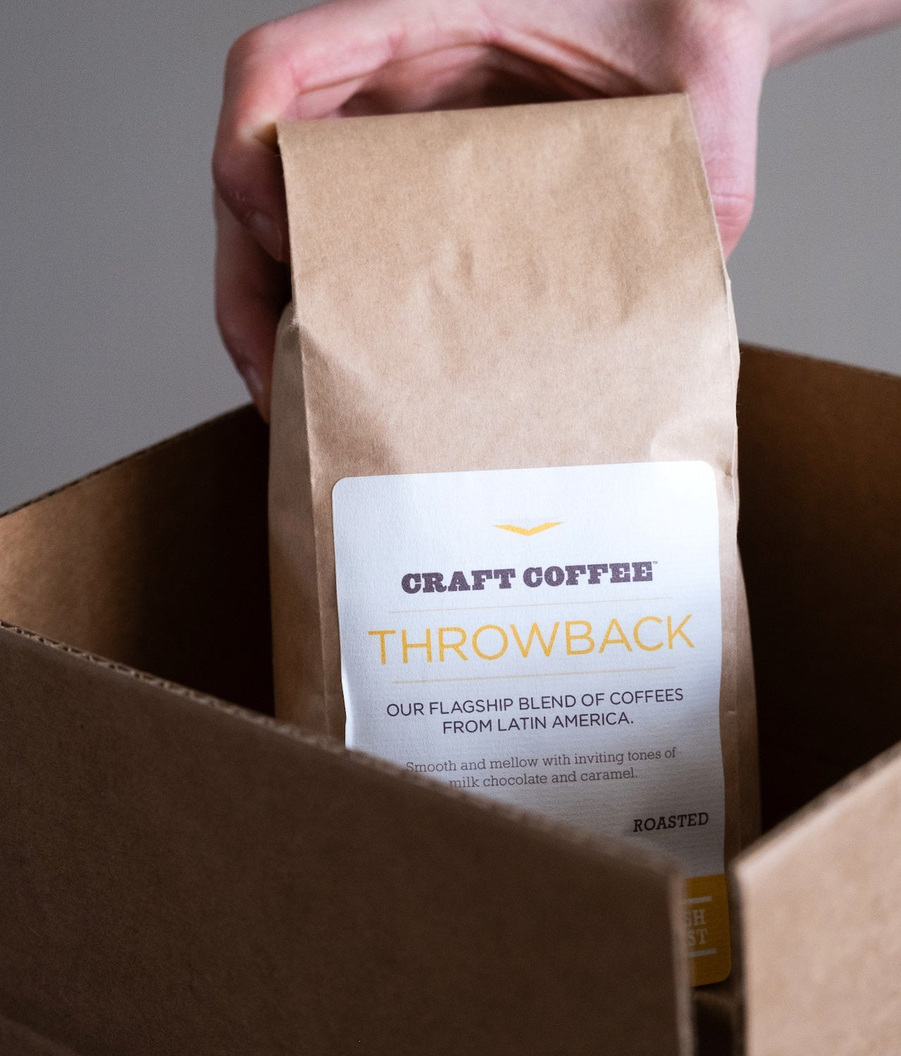 Hand pulling a bag of Craft Coffee out of its shipping box